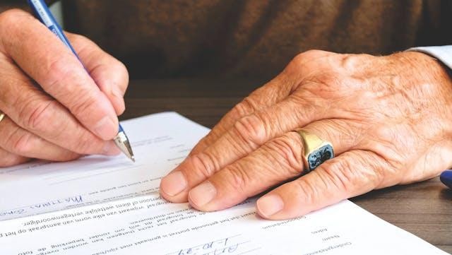 a hand signing a document